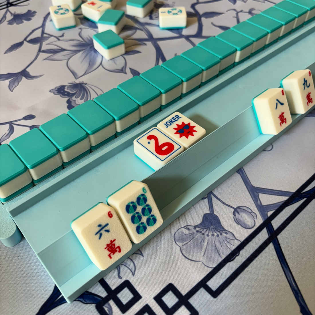 Sky Blue mahjong rack holding American mahjong tiles beside a built wall